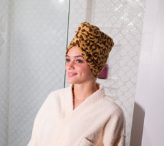 Woman in the bathroom wearing a leopard print Turbie Twist Hair Towel.