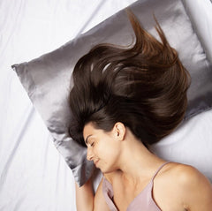 Woman laying on grey satin pillowcase